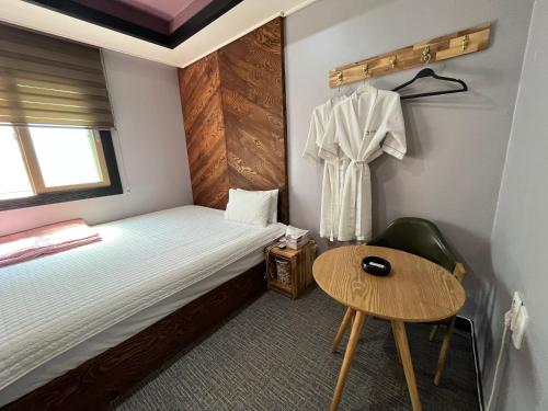 a small room with a bed and a table at Maldives Hotel & Hostel in Busan