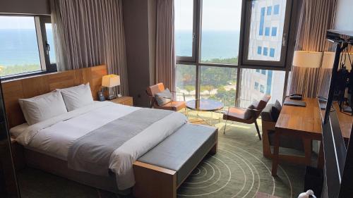 a hotel room with a bed and a desk and windows at Best Louis Hamilton Hotel Haeundae in Busan