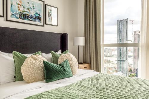a bedroom with a bed with a large window at Urban Rest Canary Wharf Apartments in London