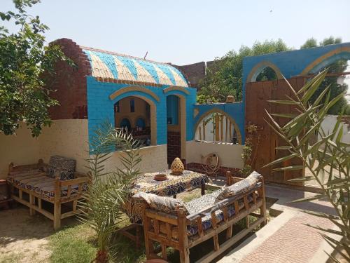 ein Haus mit einem Tisch und Bänken in einem Hof in der Unterkunft Golden Palace Garden in Luxor