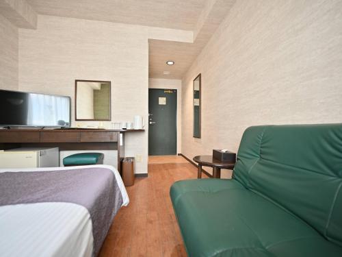 Habitación de hotel con cama y sofá verde en ホテルアビアンパナ石垣島 en Isla Ishigaki