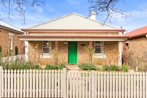 a brick house with a green door behind a fence at Ambrose On Byng - Central Location in Orange