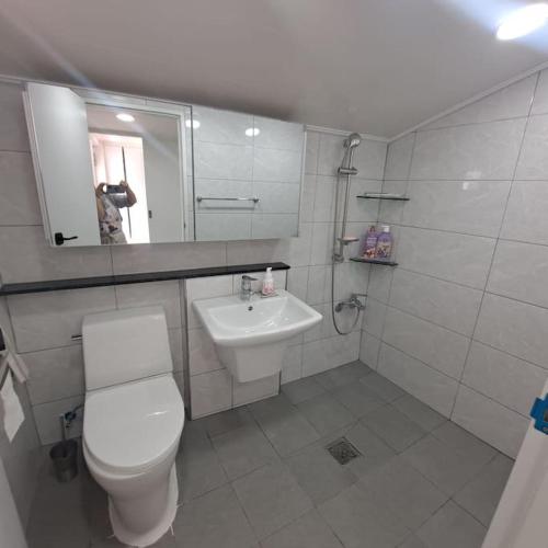 a white bathroom with a toilet and a sink at Dongpirang Private Pension #jungangmarket #petfriendly in Tongyeong