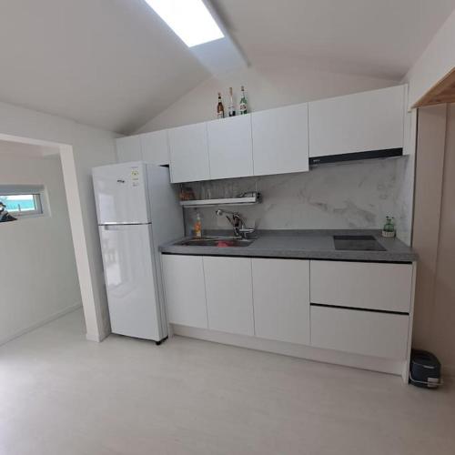 a kitchen with white cabinets and a white refrigerator at Dongpirang Private Pension #jungangmarket #petfriendly in Tongyeong