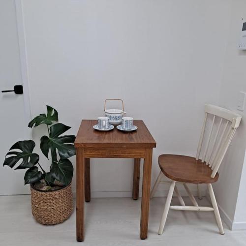 a wooden table and a chair next to a plant at Dongpirang Private Pension #jungangmarket #petfriendly in Tongyeong