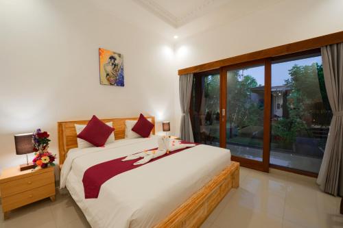 a bedroom with a large bed and a large window at Asri Guesthouse in Canggu