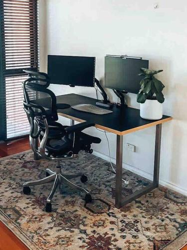 a desk with two computer monitors and a chair at Sunset views over South Fremantle in Fremantle