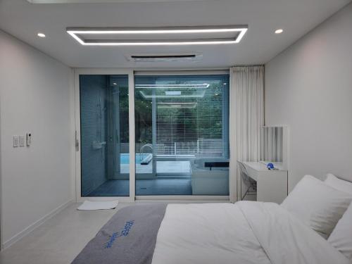 1 dormitorio con 1 cama y puerta corredera de cristal en Vesper Namhae en Namhae