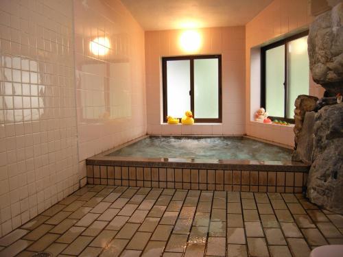 a bathroom with a hot tub with two windows at Oyado Yunosato in Shirakawa