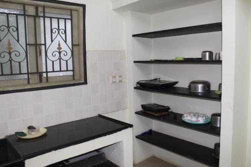 a kitchen with black shelves and a window at Centaurus Homestay near Trichy Airport in Tiruchchirāppalli