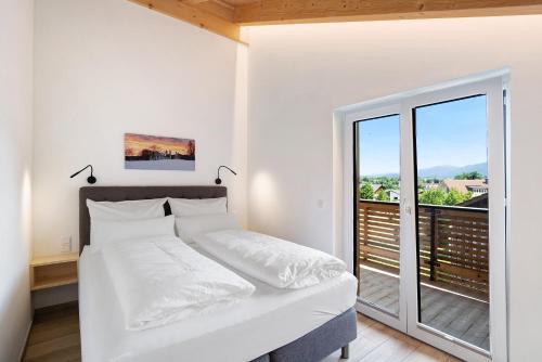 a white bedroom with a bed and a balcony at Ferienwohnung Schwaiger Almblick in Bad Tölz