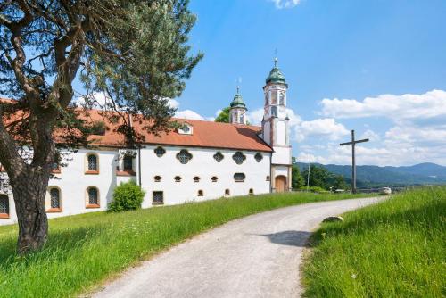 a church on a hill next to a dirt road at Ferienwohnung Wendelsteinblick in Bad Tölz