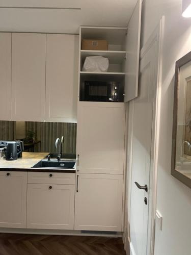 a kitchen with white cabinets and a sink at Obelų Apartamentai in Klaipėda