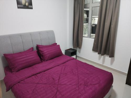 a bedroom with a purple bed with a window at Saga Laguna Condo Homestay in Port Dickson