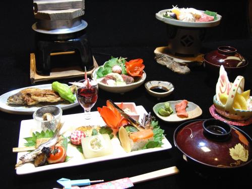 a table with plates of food and a glass of wine at Oyado Yunosato in Shirakawa