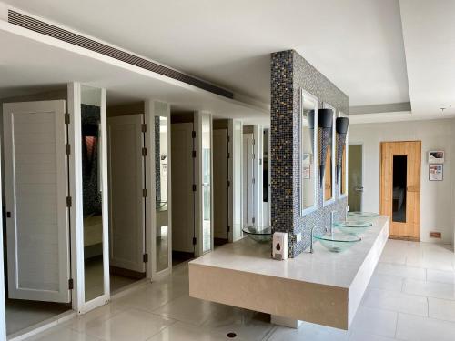 a bathroom with three sinks and a row of mirrors at Grande Caribbean Condo Resort by PTN in Pattaya South