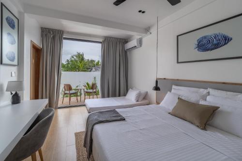 1 dormitorio blanco con 1 cama, mesa y sillas en Villa Mia Fulhadhoo, en Isla Fulhadhoo