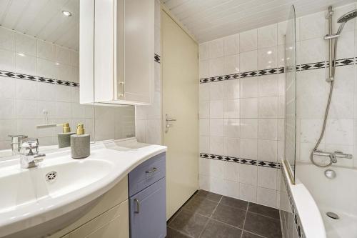 La salle de bains blanche est pourvue d'un lavabo et d'une douche. dans l'établissement 't Hoekhuisje, à Katwijk aan Zee