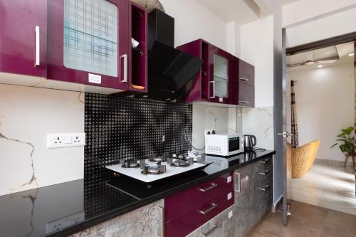 a kitchen with purple cabinets and a microwave at Daisy by Wabi Sabi Stays with Private balcony in Rishīkesh