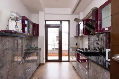 a kitchen with red cabinets and a large doorway at Daisy by Wabi Sabi Stays with Private balcony in Rishīkesh