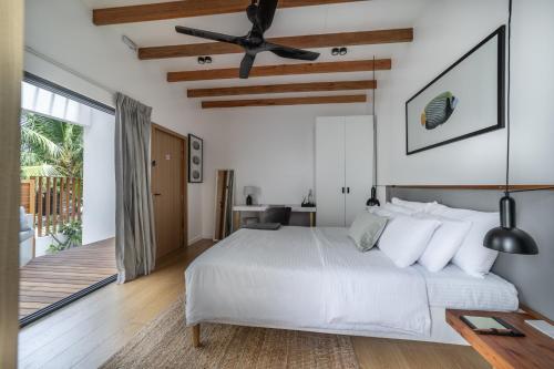 a bedroom with a white bed and a ceiling fan at Villa Mia Fulhadhoo in Fulhadhoo