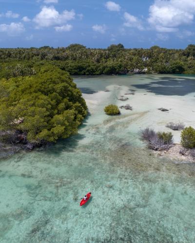 a red boat in a body of water with trees at Villa Mia Fulhadhoo in Fulhadhoo