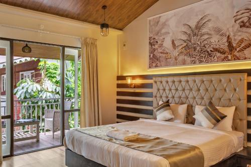 a bedroom with a large bed and a balcony at Skon Morjim Beach Resort by Orion Hotels in Morjim