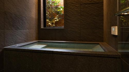 uma banheira com uma janela na casa de banho em 一日一組の隠れ宿　てらかわ em Kinosaki