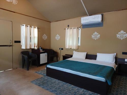 a bedroom with a bed and a desk and a chair at Shivir Aranya - Wilderness Resort in Alwar