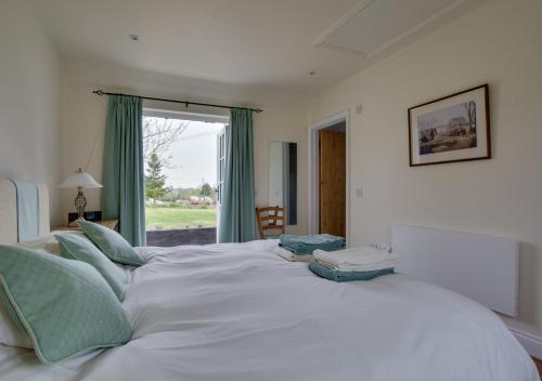 a large white bed in a room with a window at Pound Hill Cottage in Frittenden