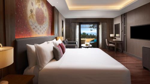 ein Hotelzimmer mit einem großen weißen Bett und einem TV in der Unterkunft Amari Vogue Krabi in Tab Kaek Beach