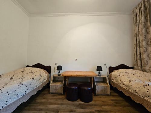 a room with two beds and a table between two beds at Guest House Aleksandre in T'mogvi