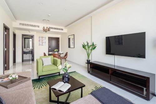 a living room with a television and a green couch at Frank Porter - Damac Celestia in Dubai