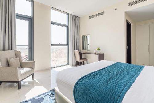 a bedroom with a bed and a chair and windows at Frank Porter - Damac Celestia in Dubai