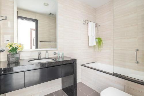 a bathroom with a sink and a tub and a mirror at Frank Porter - Damac Celestia in Dubai