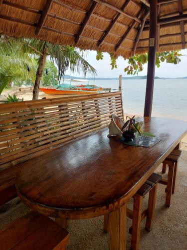 een houten tafel voor een strand met uitzicht op de oceaan bij Concepcion Divers Lodge in Busuanga