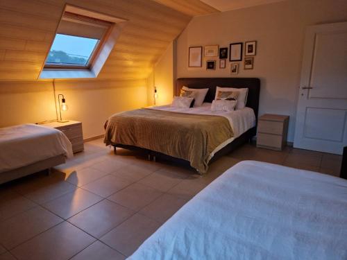 een slaapkamer met 2 bedden en een raam bij Nimary Logies in Heusden - Zolder