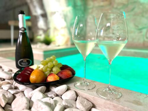 dwie szklanki białego wina obok talerza owoców w obiekcie Luxury Suite Alfieri w mieście Martina Franca