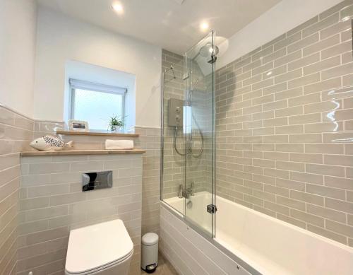 a bathroom with a toilet and a glass shower at Idyllic Country Cottage near Marazion & St Ives in Penzance