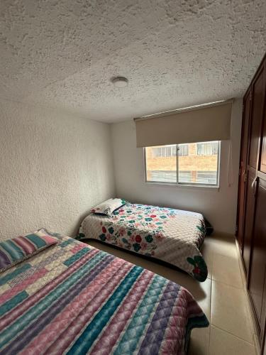 a small bedroom with two beds and a window at Apartamento cómodo con excelente ubicación in Bucaramanga