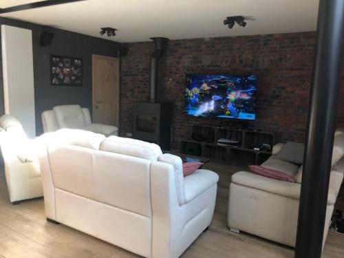 ein Wohnzimmer mit weißen Möbeln und einem TV in der Unterkunft Chez Raoul - Ancienne Grange in Pont-à-Celles
