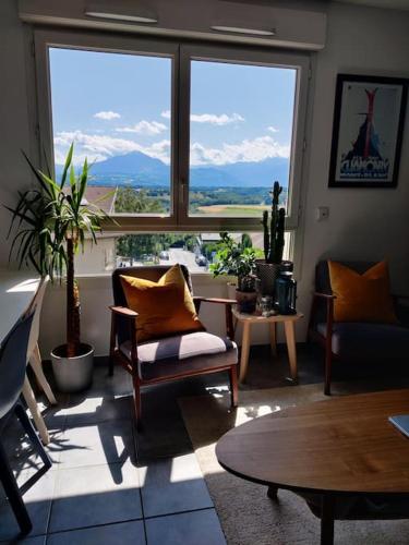een woonkamer met stoelen en een groot raam bij Charmant appartement avec magnifique vue in Monnetier-Mornex