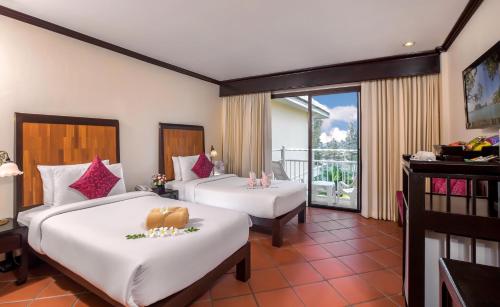 a hotel room with two beds and a balcony at The Front Village - SHA Plus in Karon Beach