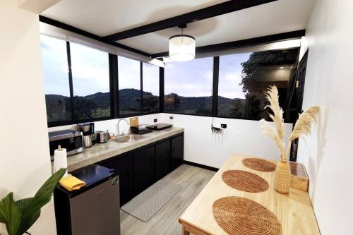 蒙特韋爾德哥斯達黎加的住宿－Calma, Monteverde - Expect Serenity Here，厨房配有桌子和一些窗户。