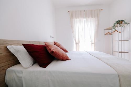 a white bed with red and white pillows on it at PRIMO RENT ROOM in Mesagne