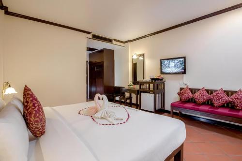 a bedroom with a white bed and a couch at The Front Village - SHA Plus in Karon Beach