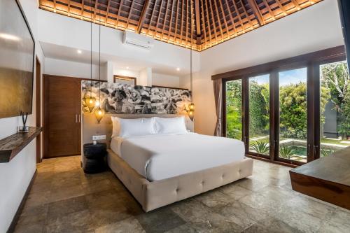 ein Schlafzimmer mit einem großen weißen Bett und Fenstern in der Unterkunft Villa Iris by BaliSuperHost in Dalung