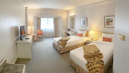 a hotel room with two beds and a television at Lanna Palace 2004 in Chiang Mai
