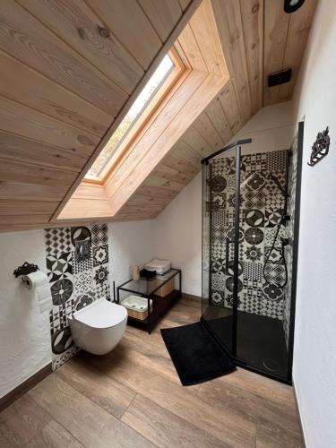 a bathroom with a toilet and a shower with a skylight at Bieszczadzki Hoży Ryś Apartamenty in Berezka