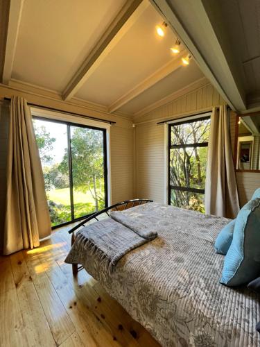 a bedroom with a bed and large windows at Moonriver Cottage, Prime Lagoon Views & Solar Power in Knysna